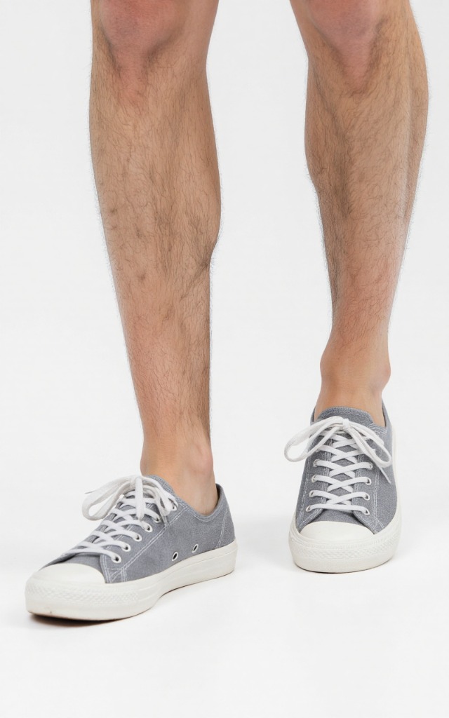 A male model wearing Canvas shoes, against a white background, with a close   up of the feet